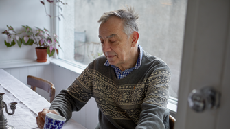 Imagem de pessoa sentada à mesa a beber um chá